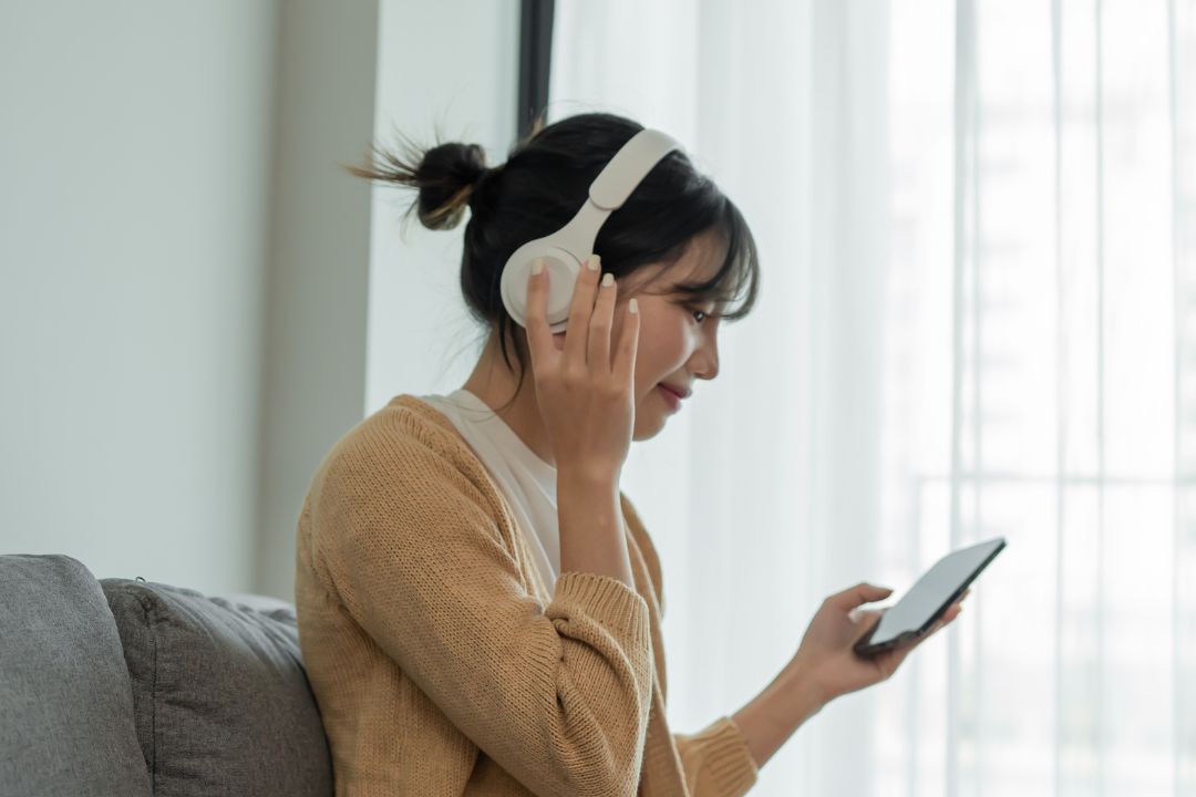 A woman listening through headphones while following a program on her phone